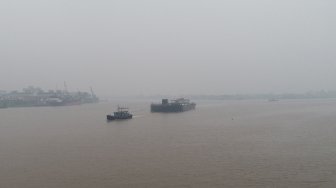 Dua kapal melintasi Sungai Kapuas yang diselimuti kabut asap pekat di Pontianak, Kalimantan Barat, Senin (9/9). [ANTARA FOTO/Rana Larasati]