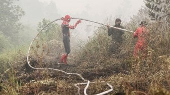 Seorang warga mengenakan kostum superhero Spiderman membantu petugas BPBD Riau dan TNI Kodim 0313 Kampar saat memadamkan kebakaran lahan gambut di Rimbo Panjang, Kabupaten Kampar, Riau, Kamis (12/9). [ANTARA FOTO/Rony Muharrman]