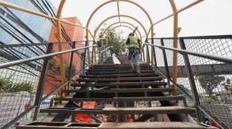 Pekerja menyelesaikan proyek jembatan penyeberangan orang (JPO) di kawasan Pasar Minggu, Jakarta Selatan, Selasa (17/9). [Suara.com/Angga Budhiyanto]
