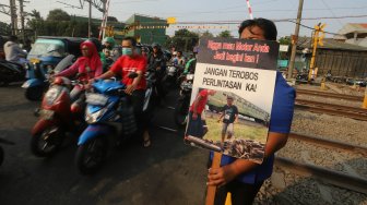 Petugas KAI Daop 1 Jakarta melakukan sosialisasi keselamatan di perlintasan sebidang Bukit Duri Manggarai, Jakarta, Selasa (17/9). [Suara.com/Arya Manggala]