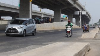 Sejumlah kendaraan melintas di samping trotoar yang berada di tengah jalan di Jalan Inspeksi Saluran Kalimalang, Jakarta, Rabu (18/9). [Suara.com/Angga Budhiyanto]