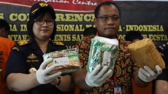 Kasatgas NIC Dittipid Narkoba Bareskrim Polri AKBP Victor Siagian (kanan) didampingi Kepala Kantor Wilayah Direktorat Jendral Bea dan Cukai (DJBC) Sumatera Utara Oza Olavia (kiri)  menunjukkan barang bukti berupa narkoba jenis sabu dan ekstasi saat rilis kasus penggagalan penyelundupan narkoba dari Malaysia di Bareskrim Polri, Jakarta, Jumat (20/9). [Suara.com/Angga Budhiyanto]