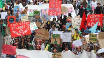 Aktivis dari berbagai organisasi lingkungan berjalan menuju Taman Aspirasi Monas saat aksi terkait krisis iklim di Jalan Medan Merdeka Barat, Jakarta Pusat, Jumat (20/9). [Suara.com/Arya Manggala]