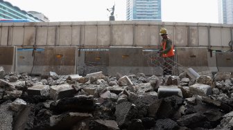 Pekerja menyelesaikan proyek revitalisasi trotoar di sekitaran Bundaran Hotel Indonesia, Jakarta, Minggu (22/9). [Suara.com/Angga Budhiyanto]
