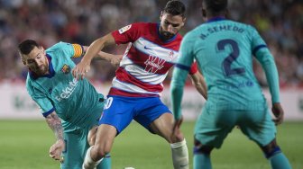 Pemain tengah Granada, Yangel Herrera (kiri) bersaing dengan pemain depan Barcelona Lionel Messi selama pertandingan sepak bola liga Spanyol antara Granada melawan Barcelona di Stadion Nuevo Los Carmenes, Granada, Spanyol, Minggu (22/9) dini hari WIB. [GUERRERO JORGE]