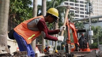 Pekerja menyelesaikan proyek revitalisasi trotoar di sekitaran Bundaran Hotel Indonesia, Jakarta, Minggu (22/9). [Suara.com/Angga Budhiyanto]