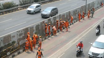 Petugas PPSU membersihkan coretan yang mengotori pembatas jalan pasca unjuk rasa mahasiswa yang berujung ricuh di depan Kompleks Parlemen, Senayan, Jakarta, Rabu (25/9). [Suara.com/Arya Manggala]