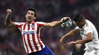 Bek Atletico Madrid Mario Hermoso dan gelandang Real Madrid Brasil Casemiro melompat untuk mendapatkan bola selama pertandingan sepak bola liga Spanyol antara Atletico Madrid melawan Real Madrid di stadion Wanda Metropolitano, Madrid, Spanyol, Minggu (29/9) dini hari WIB. [OSCAR DEL POZO / AFP]