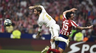 Bek Real Madrid Sergio Ramos dan pemain belakang Atletico Madrid Stefan Savic melompat untuk mendapatkan bola selama pertandingan sepak bola liga Spanyol antara Atletico Madrid melawan Real Madrid di stadion Wanda Metropolitano, Madrid, Spanyol, Minggu (29/9) dini hari WIB. [OSCAR DEL POZO / AFP]