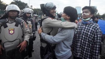 Polisi dan mahasiswa berpelukan saat unjuk rasa di depan gedung Parlemen, Jakarta, Senin (30/9). [ANTARA FOTO/Indrianto Eko Suwarso]