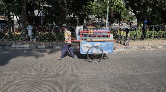 Warga melintas di depan kawat berduri yang terpasang di depan Gedung Badan Pemeriksa Keuangan (BPK), Jakarta, Rabu (2/10).[Suara.com/Angga Budhiyanto]