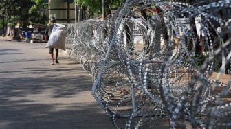 Warga melintas di depan kawat berduri yang terpasang di depan Gedung Badan Pemeriksa Keuangan (BPK), Jakarta, Rabu (2/10).[Suara.com/Angga Budhiyanto]