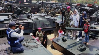 Sejumlah warga menaiki tank milik TNI yang terparkir di Landasan Udara Halim Perdanakusuma, Jakarta Timur, Sabtu (5/10). [Suara.com/Angga Budhiyanto]