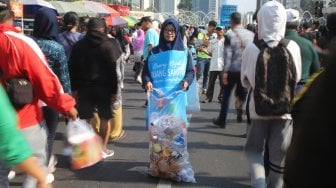 Relawan Komunitas Clean The City mengumpulkan sampah saat Car Free Day di Bundaran HI, Jakarta, Minggu (6/10). [Suara.com/Arya Manggala]