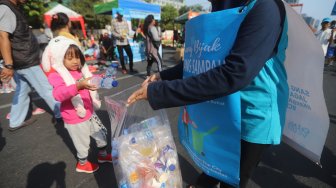 Relawan Komunitas Clean The City mengumpulkan sampah saat Car Free Day di Bundaran HI, Jakarta, Minggu (6/10). [Suara.com/Arya Manggala]