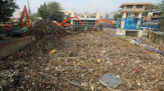 Pekerja dengan alat berat mengangkut sampah yang menumpuk di Pintu Air Manggarai, Jakarta, Rabu (9/10). [Suara.com/Arya Manggala]