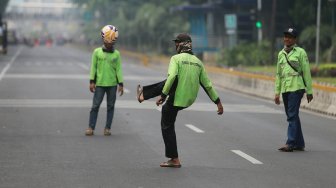 Sejumlah petugas Dinas Kehutanan Provinsi DKI Jakarta bermain sepak bola di tengah Jalan Medan Merdeka Barat yang ditutup, Jakarta, Kamis (10/9). [Suara.com/Arya Manggala]