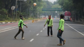 Sejumlah petugas Dinas Kehutanan Provinsi DKI Jakarta bermain sepak bola di tengah Jalan Medan Merdeka Barat yang ditutup, Jakarta, Kamis (10/9). [Suara.com/Arya Manggala]