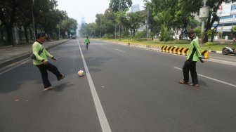 Sejumlah petugas Dinas Kehutanan Provinsi DKI Jakarta bermain sepak bola di tengah Jalan Medan Merdeka Barat yang ditutup, Jakarta, Kamis (10/9). [Suara.com/Arya Manggala]