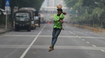 Sejumlah petugas Dinas Kehutanan Provinsi DKI Jakarta bermain sepak bola di tengah Jalan Medan Merdeka Barat yang ditutup, Jakarta, Kamis (10/9). [Suara.com/Arya Manggala]