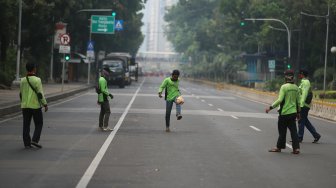 Sejumlah petugas Dinas Kehutanan Provinsi DKI Jakarta bermain sepak bola di tengah Jalan Medan Merdeka Barat yang ditutup, Jakarta, Kamis (10/9). [Suara.com/Arya Manggala]