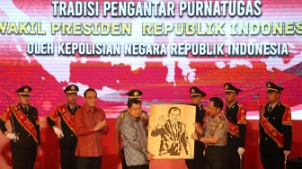 Wakil Presiden Republik Indonesia, Drs. H. Muhammad Jusuf Kalla menerima cenderamata berupa lukisan saat Tradisi Pengantar Purna Tugas Wakil Presiden di STIK-PTIK, Jakarta Selatan, Jumat (18/10). (Suara.com/Angga Budhiyanto)
