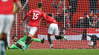 Striker Manchester United Marcus Rashford (C) mencetak gol pembuka melewati kiper Liverpool Alisson Becker (kiri) selama pertandingan sepak bola Liga Inggris antara Manchester United melawan Liverpool di Old Trafford, Manchester, Inggris, Senin (21/10). dini hari WIB.
[Oli SCARFF / AFP]