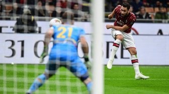 Pemain depan AC Milan Hakan Calhanoglu (R) menembak untuk membuka skor melewati kiper Gabriel Lecce selama pertandingan sepak bola Serie A Italia AC Milan melawan Lecce di Stadion San Siro, Milan, Italia, Senin (21/10) dini hari WIB. [Miguel MEDINA / AFP]
