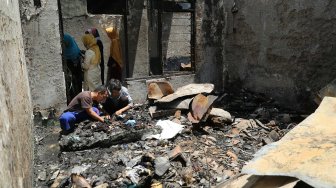 Warga berada di antara puing sisa kebakaran di Jalan Setia, Bidara Cina, Jatinegara, Jakarta, Selasa (22/10). [Suara.com/Arya Manggala]