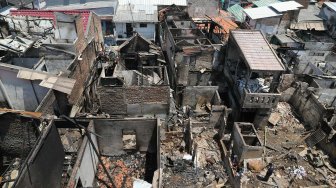 Warga berada di antara puing sisa kebakaran di Jalan Setia, Bidara Cina, Jatinegara, Jakarta, Selasa (22/10). [Suara.com/Arya Manggala]