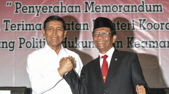 Menko Polhukam Mahfud MD (kanan) berjabat tangan dengan pejabat lama Wiranto saat serah terima jabatan di kantor Kemenko Polhukam, Jakarta, Rabu (23/10). [ANTARA FOTO/Hafidz Mubarak]