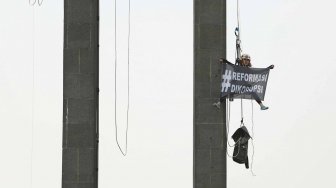 Aktivis Greenpeace membentangkan spanduk di Patung Selamat Datang, di Bundaran HI, Jakarta, Rabu (23/10).[Suara.com/Arya Manggala]