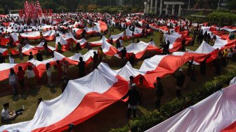 Sejumlah pelajar membentangkan bendera Merah Putih saat digelar Upacara Sumpah Merah Putih dalam rangka peringatan Hari Sumpah Pemuda di lapangan Tugu Pahlawan, Surabaya, Jawa Timur, Sabtu (26/10). [ANTARA FOTO/Zabur Karuru]