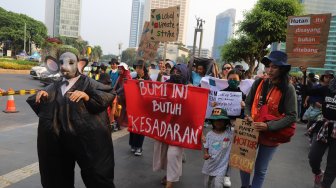 Aktivis dari berbagai organisasi lingkungan berjalan menuju Taman Aspirasi Monas saat aksi terkait krisis iklim di Kawasan Bundaran HI, Jakarta, Sabtu (26/10). [Suara.com/Arya Manggala]