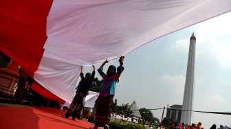 Sejumlah pelajar membentangkan bendera Merah Putih saat digelar Upacara Sumpah Merah Putih dalam rangka peringatan Hari Sumpah Pemuda di lapangan Tugu Pahlawan, Surabaya, Jawa Timur, Sabtu (26/10). [ANTARA FOTO/Zabur Karuru]