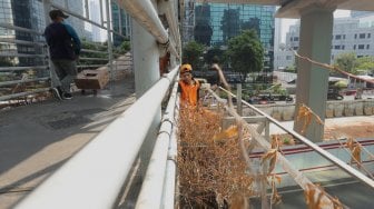 Petugas Kebersihan membersihkan jembatan penyeberangan orang (JPO) yang tidak terawat dan menimbulkan bau pesing di kawasan Karet Kuningan, Jakarta, Rabu (30/10). [Suara.com/Angga Budhiyanto]