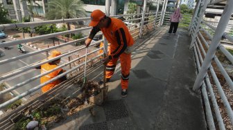 Petugas Kebersihan membersihkan jembatan penyeberangan orang (JPO) yang tidak terawat dan menimbulkan bau pesing di kawasan Karet Kuningan, Jakarta, Rabu (30/10). [Suara.com/Angga Budhiyanto]