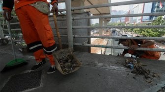 Petugas Kebersihan membersihkan jembatan penyeberangan orang (JPO) yang tidak terawat dan menimbulkan bau pesing di kawasan Karet Kuningan, Jakarta, Rabu (30/10). [Suara.com/Angga Budhiyanto]