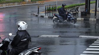 Pengendara sepeda motor mengenakan jas hujan saat melintas di Jalan Sisisingamangaraja, Kebayoran Baru, Jakarta Selatan, Jumat (1/11). [Suara.com/Angga Budhiyanto]