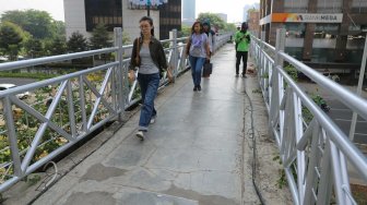 Pejalan kaki melintas di Jembatan Penyeberangan Orang (JPO) tanpa atap di Jalan Sudirman, Jakarta Pusat, Rabu (6/11). [Suara.com/Arya Manggala]
