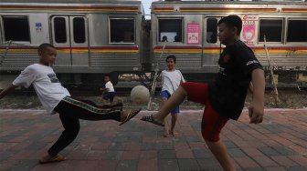 Sejumlah anak bermain sepak bola di pinggir rel kereta api di kawasan Duri, Jakarta Barat, Selasa (5/11).  [Suara.com/Angga Budhiyanto]
