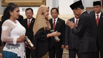 Presiden Joko Widodo (kanan) menyerahkan plakat anugerah gelar pahlawan nasional kepada ahli waris KH Masjkur di Istana Negara, Jakarta, Jumat (8/11). [ANTARA FOTO/Puspa Perwitasari]