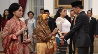 Presiden Joko Widodo (kanan) menyerahkan plakat anugerah gelar pahlawan nasional kepada ahli waris Prof KH Abdul Kahar Mudzakkir di Istana Negara, Jakarta, Jumat (8/11). [ANTARA FOTO/Puspa Perwitasari]