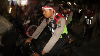 Polisi bersama sejumlah anggota komunitas pecinta sepeda 'Kediri Night Ride' melintasi rute yang telah ditentukan di Kota Kediri, Jawa Timur, Sabtu (9/11) malam. [ANTARA FOTO/Prasetia Fauzani]