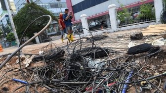 Pejalan kaki melintas di antara kabel fiber optik yang berada di jalur pedestrian, kawasan Kramat Raya, Jakarta, Senin (11/11). [ANTARA FOTO/Muhammad Adimaja]