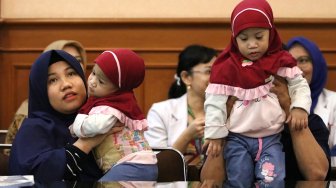 Bayi kembar siam asal Kendari, Sulawesi Tenggara Azila (kiri) digendong ibunya Silvina Dewi dan Aqila (kanan) digendong bapaknya Jayasri di Rumah Sakit Umum Daerah (RSUD) Dr Soetomo, Surabaya, Jawa Timur, Jumat (15/11). [ANTARA FOTO/Didik Suhartono]