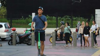 Warga menggunakan otoped atau skuter listrik di Jakarta, Jumat (15/11). [Suara.com/Arya Manggala]