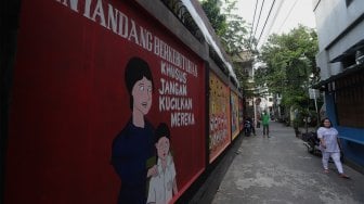 Warga melihat mural edukasi pada tembok di kawasan Pademangan Timur, Jakarta Utara, Minggu (17/11). [Suara.com/Angga Budhiyanto]