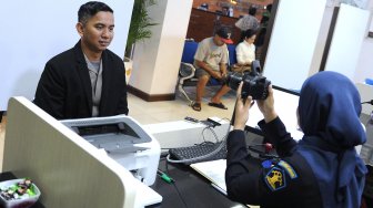 Kapolres Badung AKBP Roby Septiadi (kiri) mengikuti perekaman biometrik Paspor Elektronik (e-passport) saat penerbitan Paspor Elektronik perdana di Kantor Imigrasi Kelas I Khusus Ngurah Rai, Badung, Bali, Rabu (20/11).  [ANTARA FOTO/Fikri Yusuf]