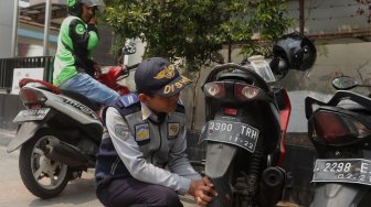 Petugas Dinas Perhubungan (Dishub) DKI Jakarta melakukan penindakan terhadap pengendara yang memarkirkan motor di trotoar di kawasan Sudirman, Jakarta, Jumat (22/11).  [Suara.com/Angga Budhiyanto]
